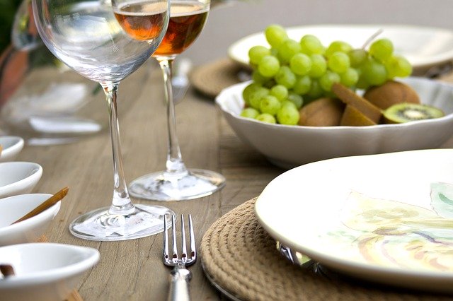 Prostřený stůl-skleničky na víno, ovoce na talíři